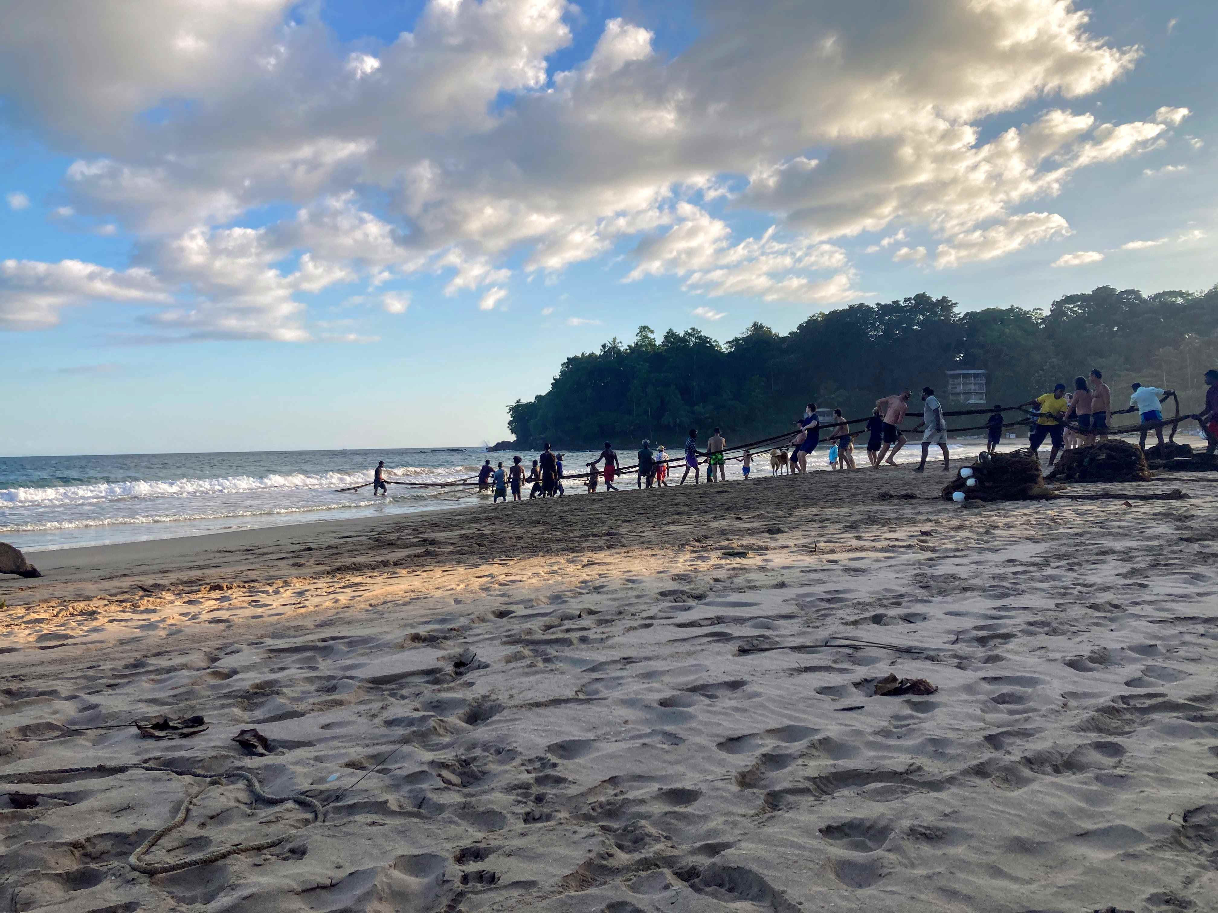 people pulling a net from the beach 